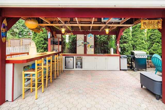 view of patio featuring fence, exterior kitchen, outdoor wet bar, and grilling area