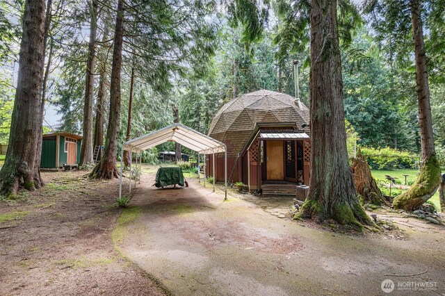 view of front of property featuring an outdoor structure, a shed, a detached carport, and dirt driveway