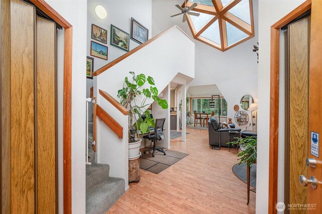 entryway featuring a ceiling fan, wood finished floors, stairway, and a towering ceiling