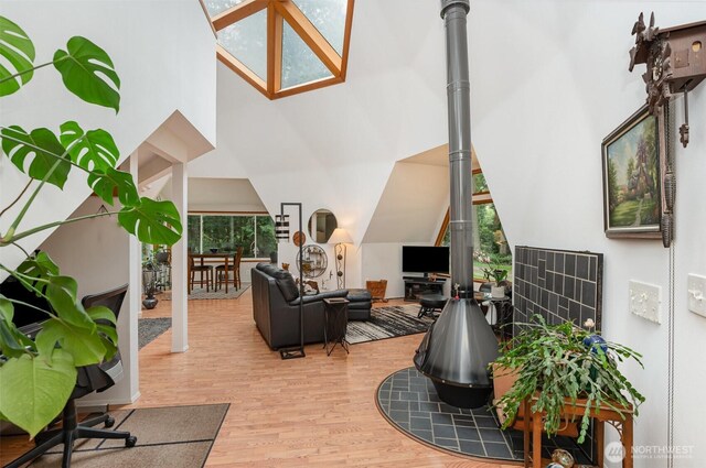 living room with a wood stove, a high ceiling, and wood finished floors