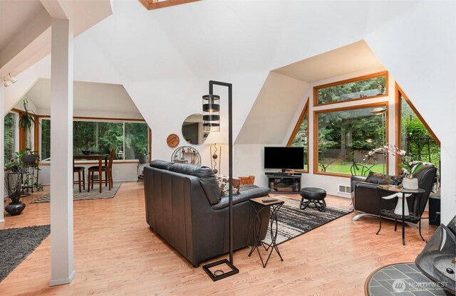 living area featuring visible vents, vaulted ceiling, and light wood-style floors