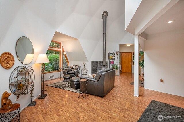 living area with light wood-type flooring, baseboards, visible vents, and vaulted ceiling