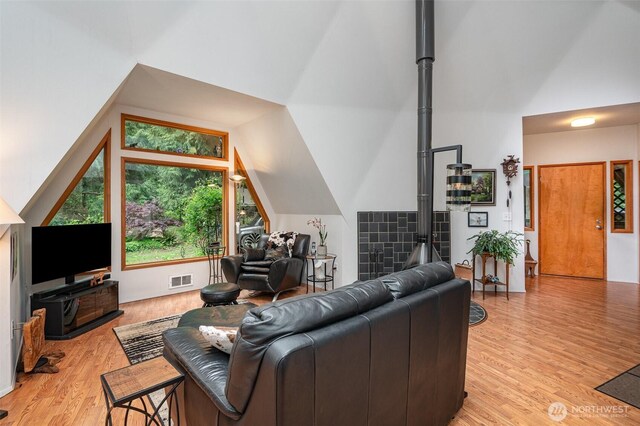 living area with vaulted ceiling, light wood finished floors, and visible vents