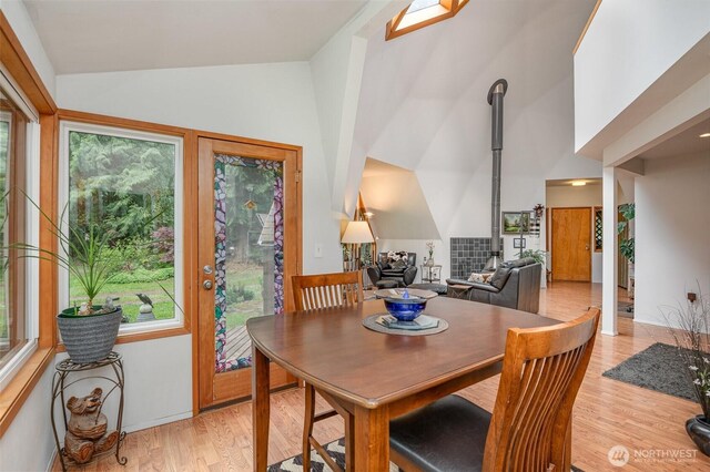 dining area with high vaulted ceiling, light wood finished floors, and a wealth of natural light