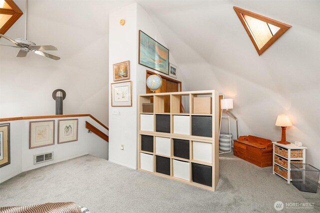 interior space with carpet floors, ceiling fan, vaulted ceiling, and visible vents