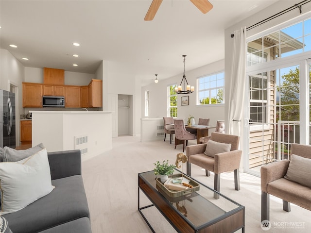 living room featuring light carpet, ceiling fan with notable chandelier, recessed lighting, and visible vents