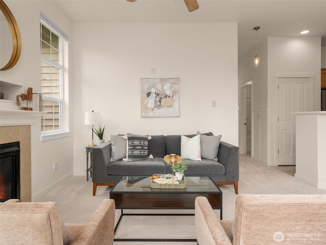 living area featuring baseboards, ceiling fan, light carpet, and a fireplace