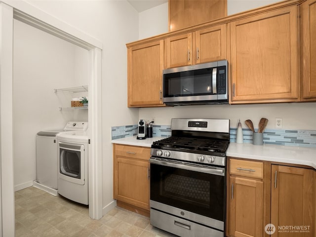 kitchen featuring brown cabinets, appliances with stainless steel finishes, light countertops, separate washer and dryer, and tasteful backsplash