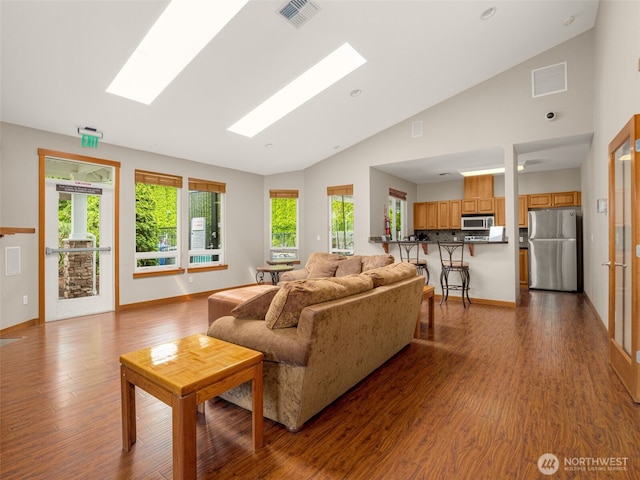 living area with visible vents, wood finished floors, and a skylight