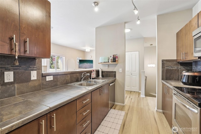 15720 Manor Way Unit C5, Lynnwood, WA 98087 - kitchen with appliances with stainless steel finishes, a sink, light wood-style flooring, decorative backsplash, and tile countertops