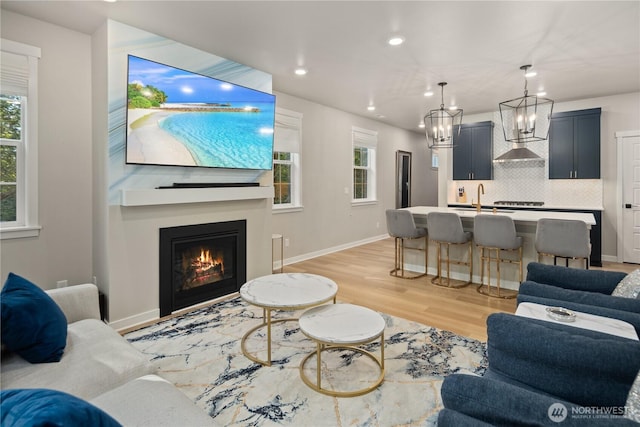 living area with recessed lighting, light wood-style flooring, plenty of natural light, and a chandelier