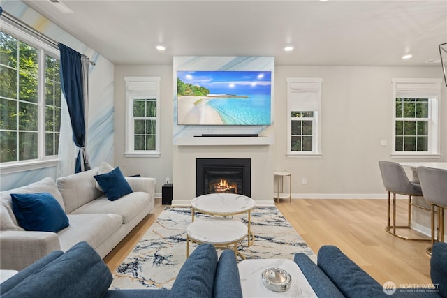 living area with a large fireplace, baseboards, recessed lighting, and wood finished floors