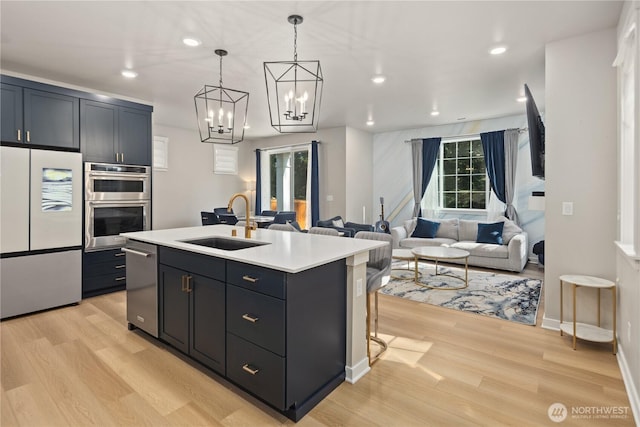 kitchen with light wood-style floors, a sink, light countertops, an inviting chandelier, and stainless steel appliances