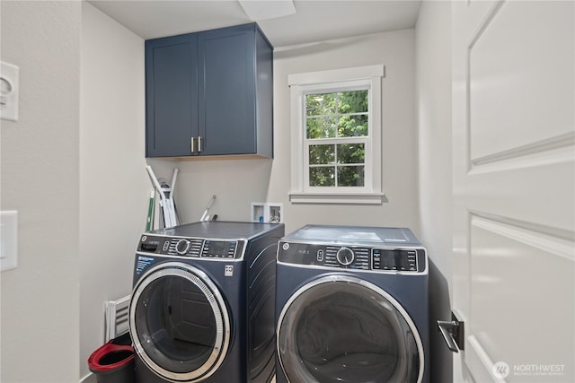 clothes washing area featuring washing machine and dryer and cabinet space
