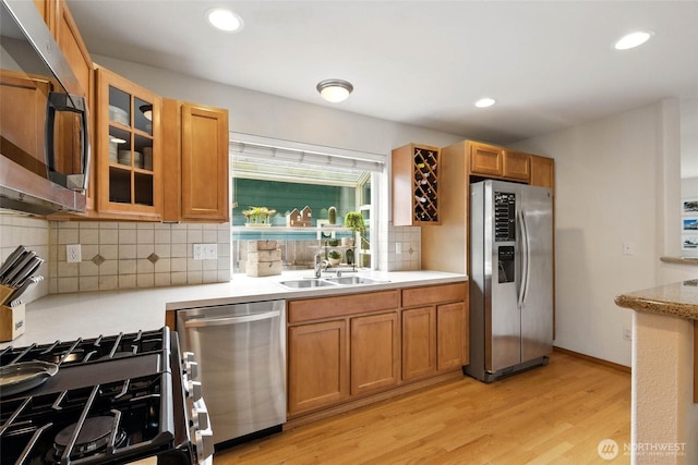 kitchen with light wood-style floors, light countertops, appliances with stainless steel finishes, and backsplash