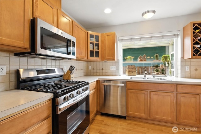 kitchen featuring light countertops, appliances with stainless steel finishes, decorative backsplash, and a sink