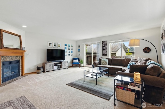 living room with a tiled fireplace, carpet flooring, and baseboards