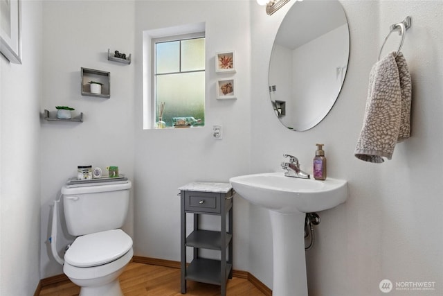 half bath with toilet, baseboards, and wood finished floors