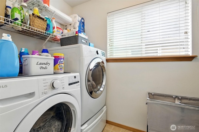 laundry room featuring light tile patterned floors, separate washer and dryer, baseboards, and laundry area