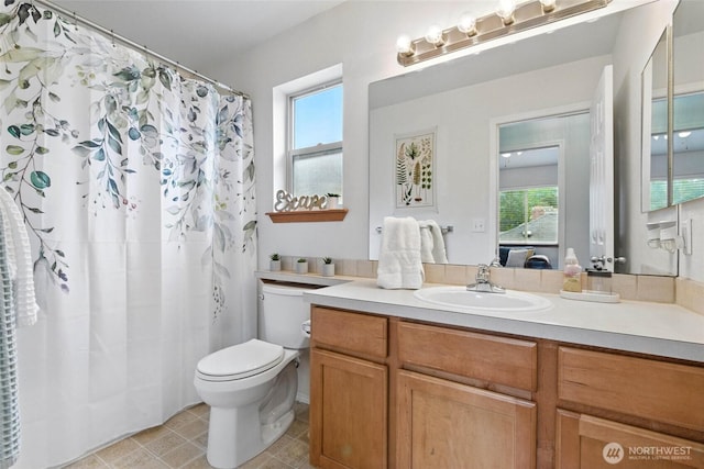 ensuite bathroom with vanity, plenty of natural light, toilet, and tile patterned flooring