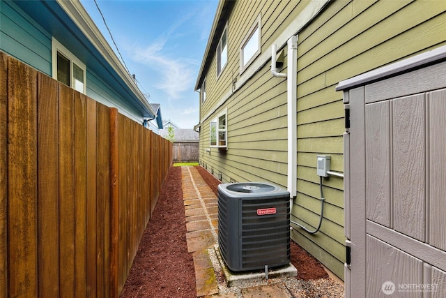 view of side of property with central AC unit and fence