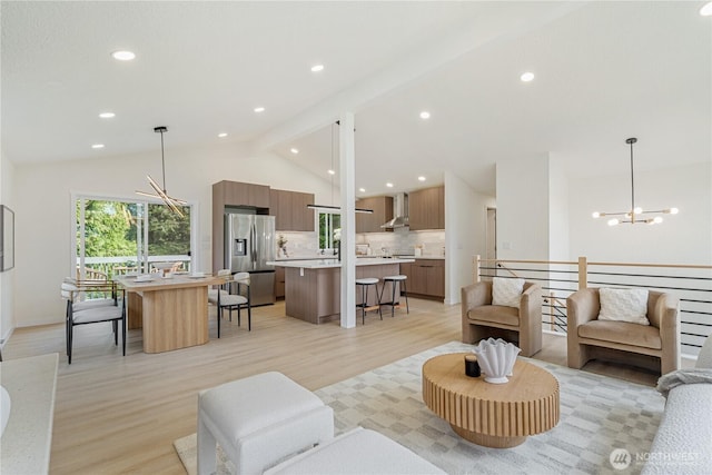 living room featuring an inviting chandelier, recessed lighting, vaulted ceiling, and light wood-type flooring