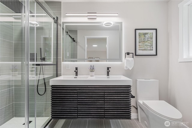full bathroom with double vanity, a stall shower, and toilet