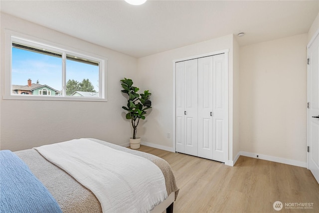 bedroom with light wood-style floors, baseboards, and a closet