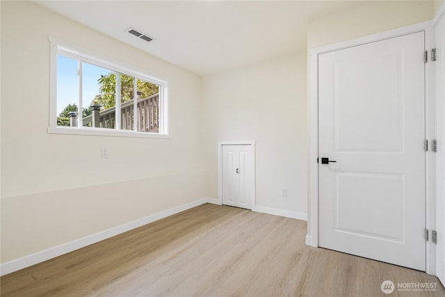 empty room with baseboards, light wood-type flooring, and visible vents