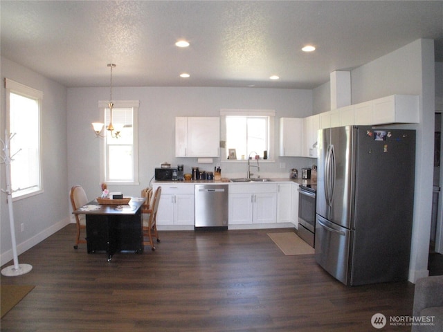 27510 X Ln, Ocean Park, WA 98640 - kitchen with a sink, dark wood-style floors, a chandelier, stainless steel appliances, and white cabinetry