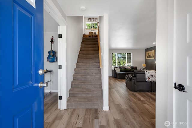 foyer featuring baseboards, stairs, and wood finished floors