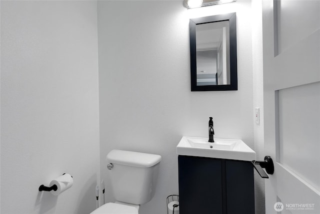 half bath featuring vanity and toilet
