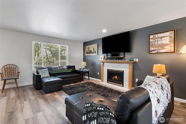 living area with recessed lighting, baseboards, a tiled fireplace, and wood finished floors