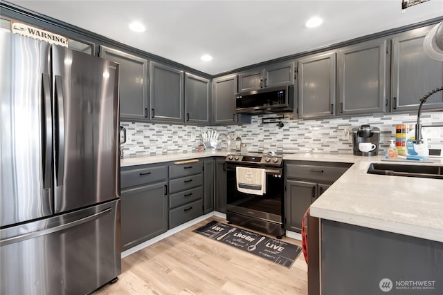 kitchen featuring decorative backsplash, a sink, gray cabinetry, light wood-style floors, and stainless steel appliances
