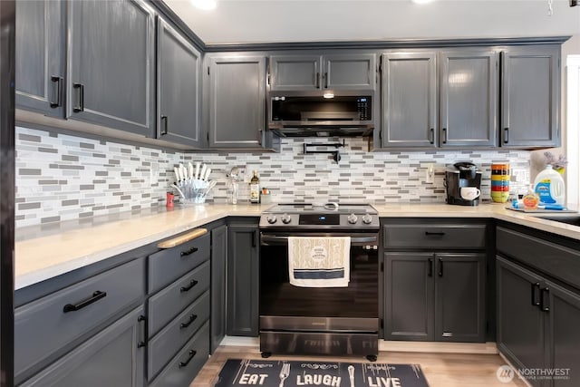 kitchen with gray cabinets, decorative backsplash, stainless steel appliances, and light wood-type flooring