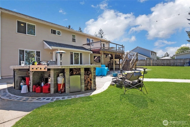 back of property featuring stairway, a deck, a yard, and fence