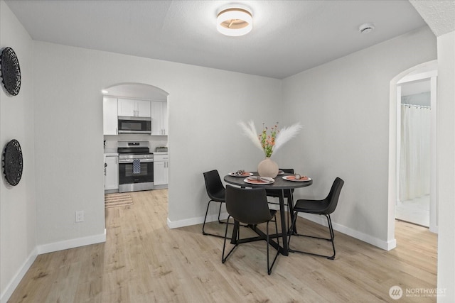 8661 State Highway 303 NE, Bremerton, WA 98311 - dining area featuring light wood-style floors, arched walkways, and baseboards