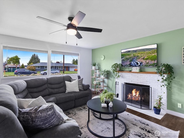 living room featuring a ceiling fan, baseboards, wood finished floors, and a fireplace