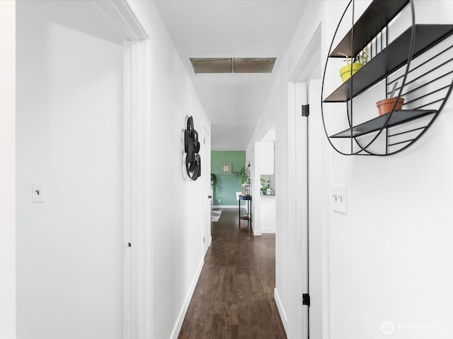 corridor featuring baseboards, dark wood finished floors, and visible vents
