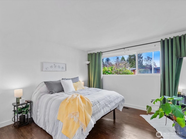 bedroom with baseboards, wood finished floors, and visible vents