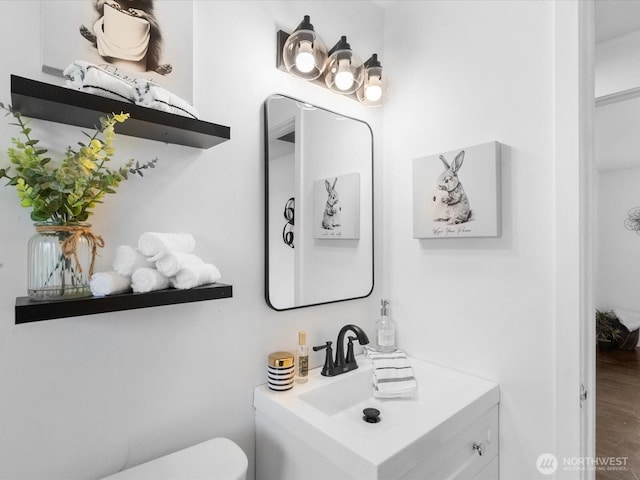 bathroom with vanity, toilet, and wood finished floors