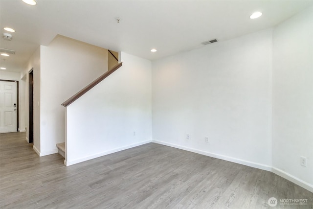 unfurnished room with visible vents, recessed lighting, wood finished floors, and stairway