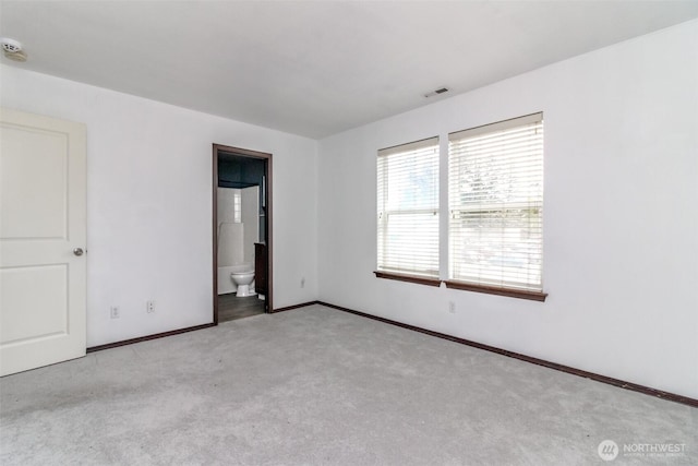 interior space featuring carpet flooring, baseboards, visible vents, and ensuite bathroom