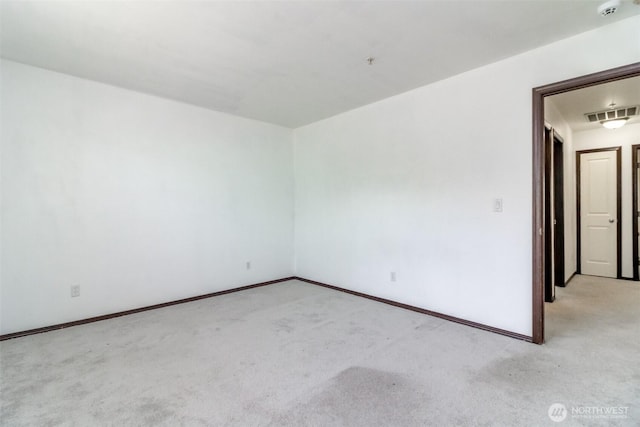 spare room featuring baseboards, visible vents, and light carpet