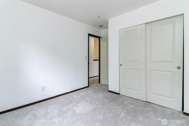 unfurnished bedroom with light colored carpet, baseboards, and a closet