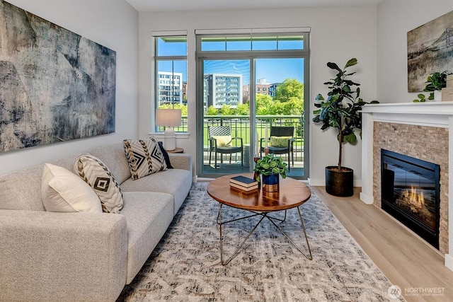 living room featuring baseboards, a tile fireplace, and wood finished floors