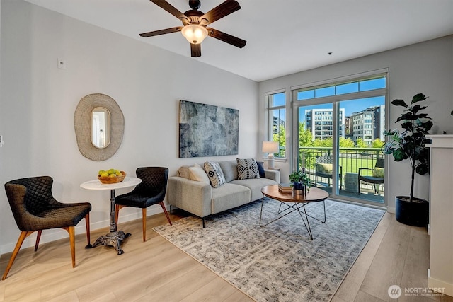 living room with light wood finished floors, baseboards, and a ceiling fan