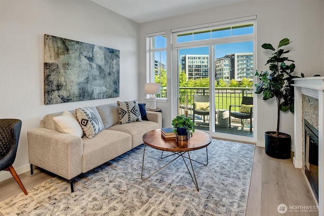 living area featuring baseboards, a glass covered fireplace, and wood finished floors