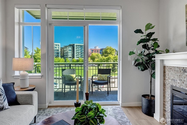 doorway to outside with wood finished floors, baseboards, a healthy amount of sunlight, and a glass covered fireplace