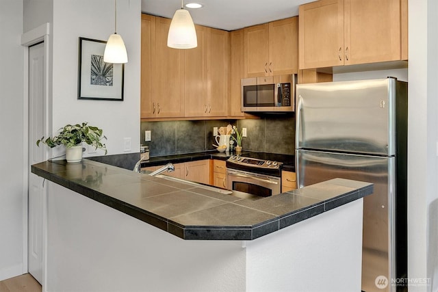kitchen featuring a peninsula, dark countertops, and appliances with stainless steel finishes
